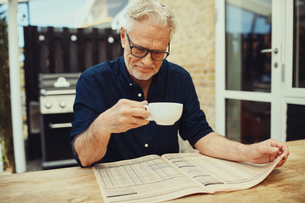 Man reading newspaper with coffee 